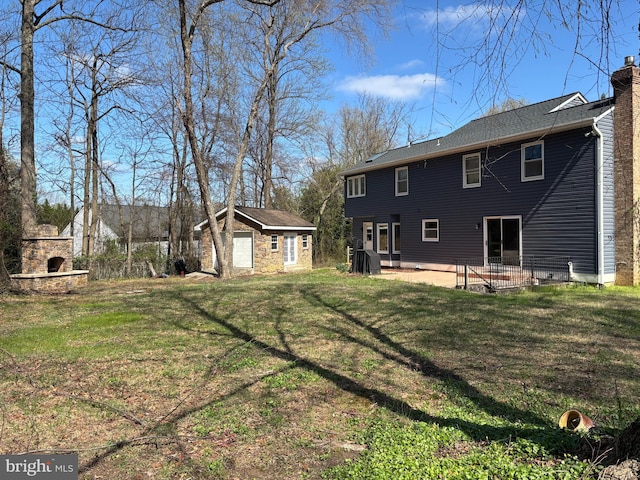 rear view of house featuring a patio area, an outdoor structure, a chimney, and a lawn