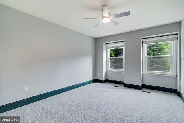 carpeted empty room with ceiling fan, baseboards, and visible vents