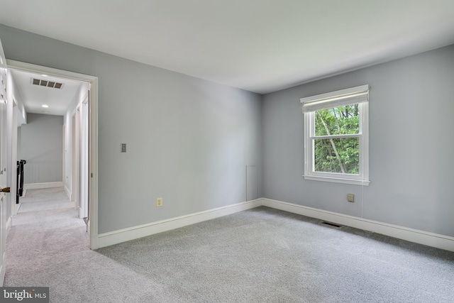 empty room with carpet, visible vents, and baseboards