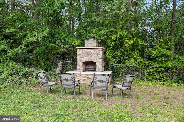 view of yard featuring an outdoor stone fireplace and fence