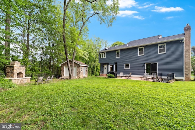 rear view of property with a detached garage, a storage shed, a patio, an outdoor stone fireplace, and a chimney