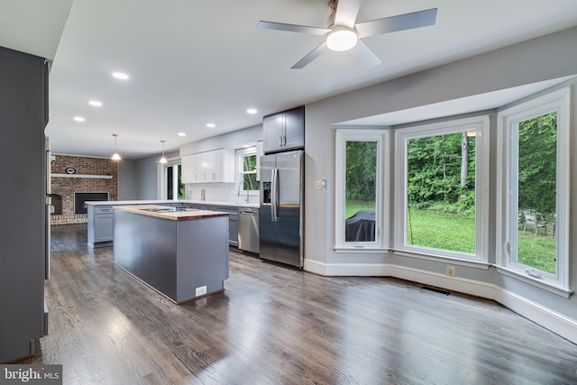 kitchen with visible vents, a brick fireplace, a center island, wooden counters, and appliances with stainless steel finishes