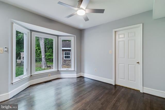 empty room featuring a ceiling fan, dark wood-style flooring, and baseboards