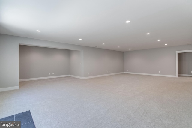 spare room with baseboards, recessed lighting, and light carpet