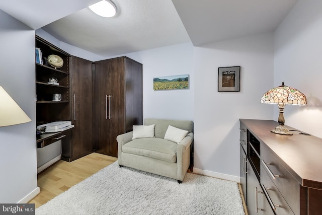 sitting room with baseboards and light wood-style floors