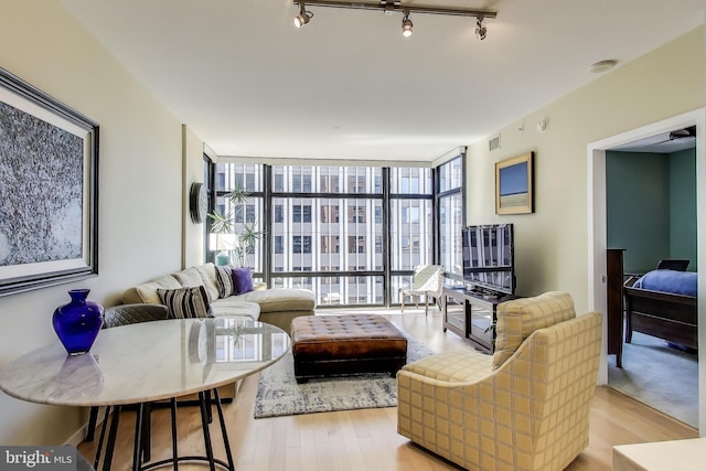 living area with visible vents, floor to ceiling windows, light wood-style floors, and track lighting