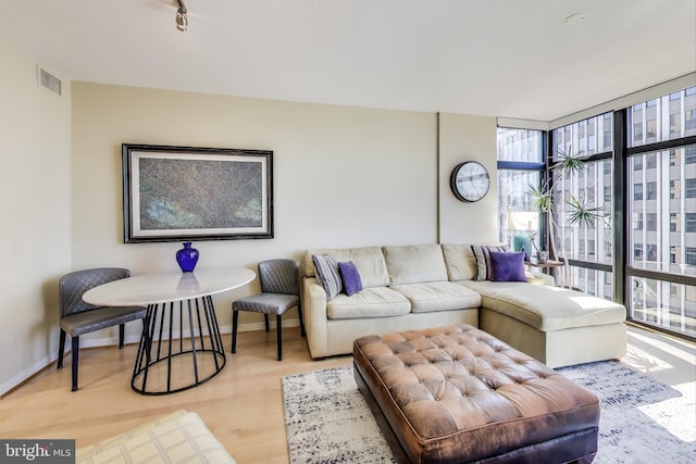 living room featuring baseboards, expansive windows, visible vents, and wood finished floors