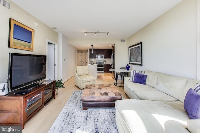 living room with visible vents, light wood-style floors, and track lighting