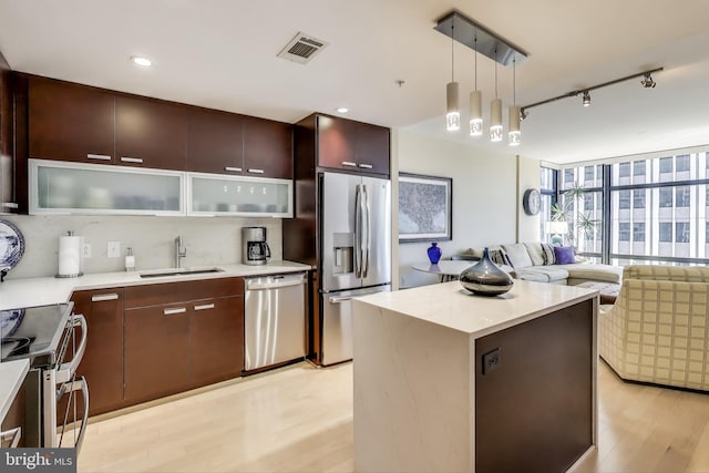 kitchen with visible vents, appliances with stainless steel finishes, a sink, light wood-type flooring, and open floor plan