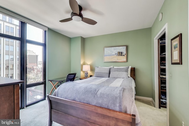 carpeted bedroom featuring a ceiling fan, baseboards, and a wall of windows