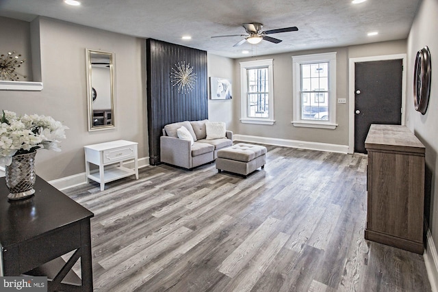 living area with a textured ceiling, baseboards, ceiling fan, wood finished floors, and recessed lighting