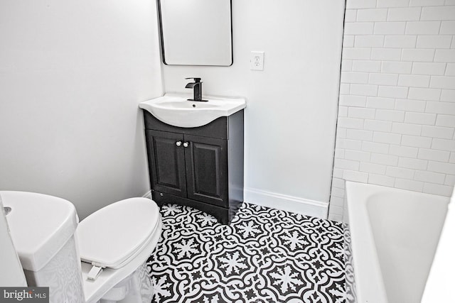 bathroom with toilet, vanity, a tub, walk in shower, and baseboards