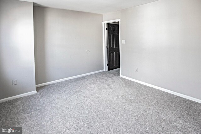 spare room with baseboards and carpet floors