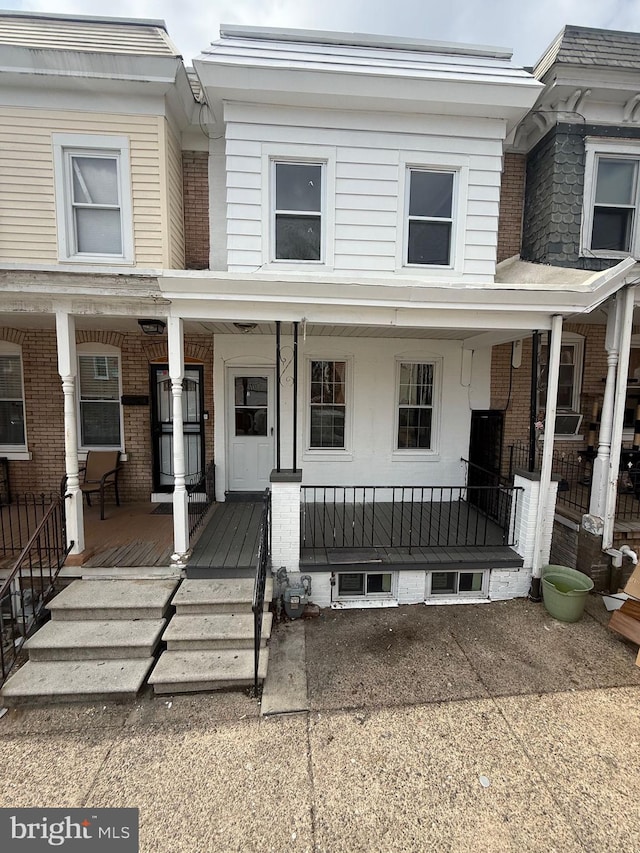 townhome / multi-family property with a porch and brick siding