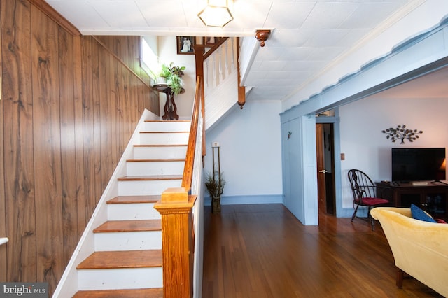 stairway featuring wood walls, baseboards, and wood finished floors