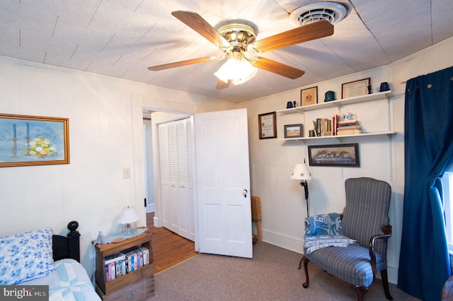 living area with visible vents, carpet floors, ornamental molding, and a ceiling fan