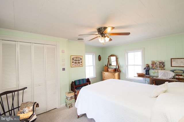 bedroom with a closet, crown molding, a ceiling fan, light carpet, and visible vents