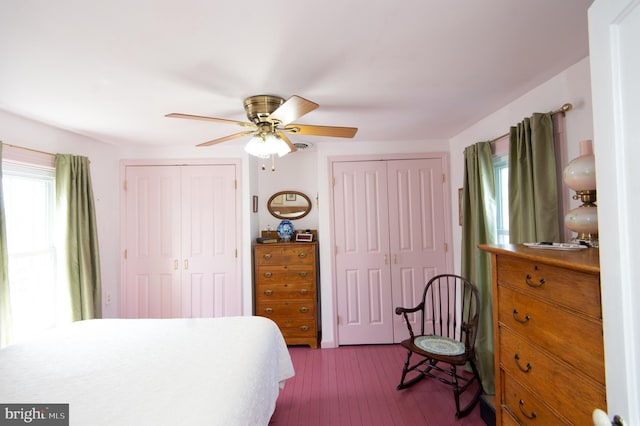 bedroom featuring multiple closets, a ceiling fan, and dark wood finished floors