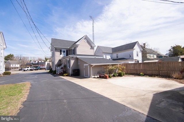 view of side of property featuring fence and roof with shingles