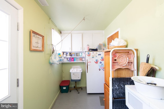 interior space featuring baseboards, visible vents, and freestanding refrigerator