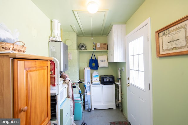 clothes washing area with attic access, washing machine and clothes dryer, and water heater