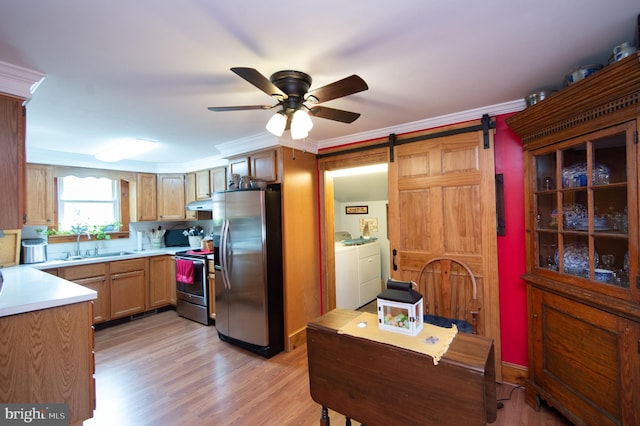 kitchen with ceiling fan, stainless steel appliances, a barn door, a sink, and washing machine and dryer