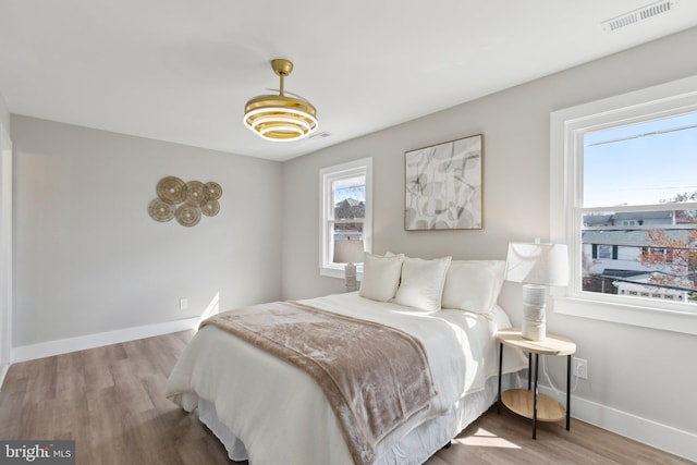 bedroom featuring wood finished floors, baseboards, and visible vents