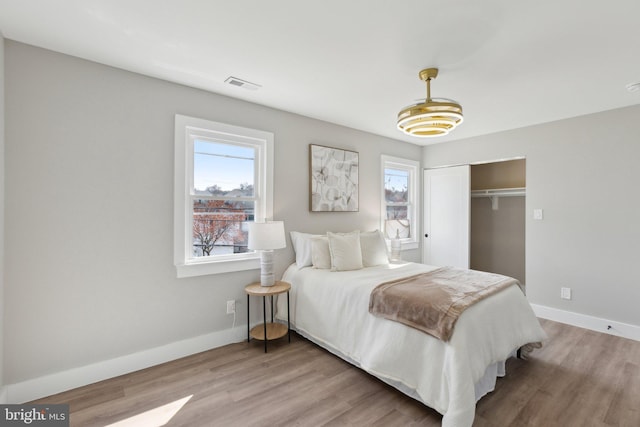 bedroom with light wood-style floors, multiple windows, and visible vents