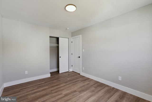 unfurnished bedroom with a closet, baseboards, and wood finished floors