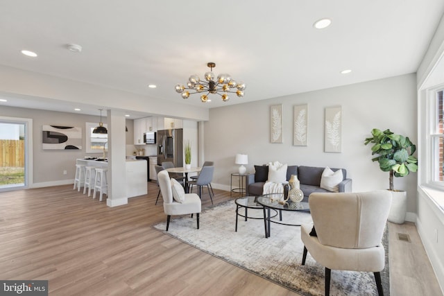 living area featuring a chandelier, baseboards, visible vents, light wood-style floors, and recessed lighting