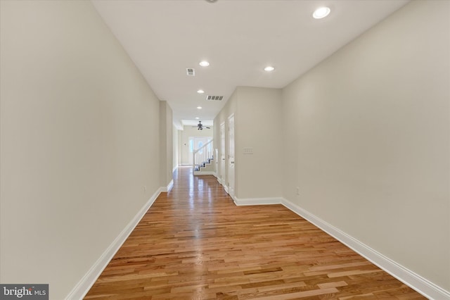 hall featuring baseboards, visible vents, light wood-style floors, and recessed lighting