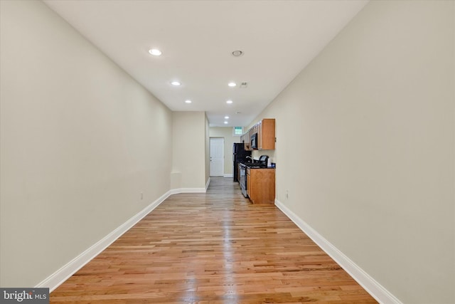 corridor featuring light wood finished floors, baseboards, and recessed lighting