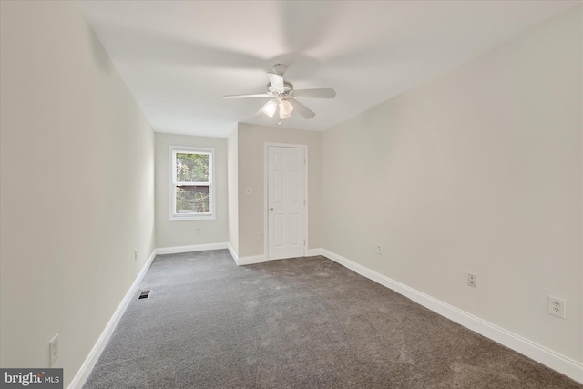 spare room featuring baseboards, ceiling fan, visible vents, and dark colored carpet