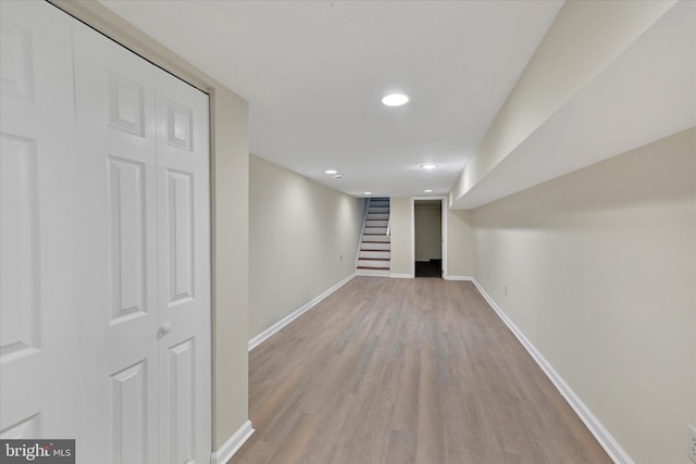 finished below grade area with light wood finished floors, baseboards, stairs, and recessed lighting