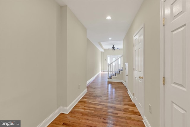 hall featuring stairway, baseboards, light wood finished floors, and recessed lighting