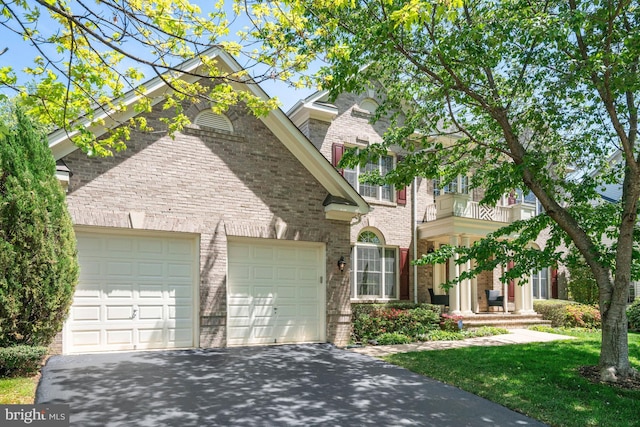 view of front of home with a balcony, an attached garage, driveway, and brick siding