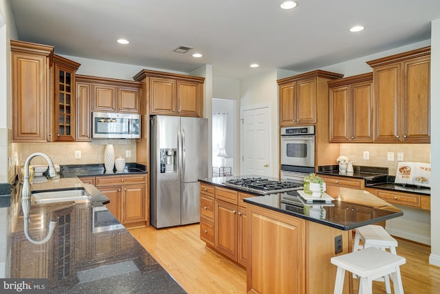 kitchen with a sink, a center island, brown cabinetry, and stainless steel appliances