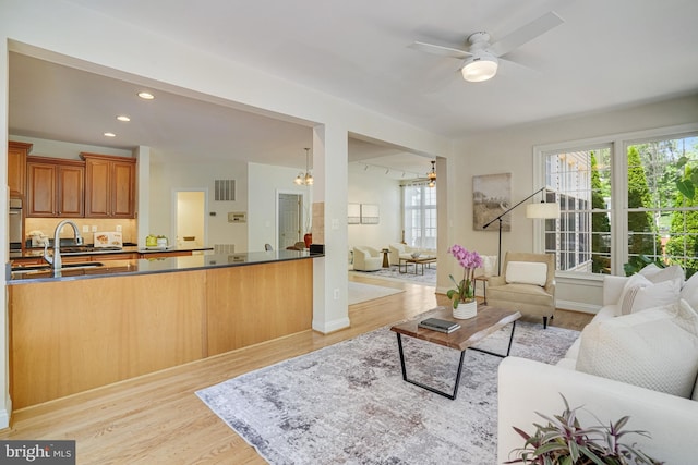 living area featuring light wood finished floors, ceiling fan with notable chandelier, recessed lighting, baseboards, and visible vents