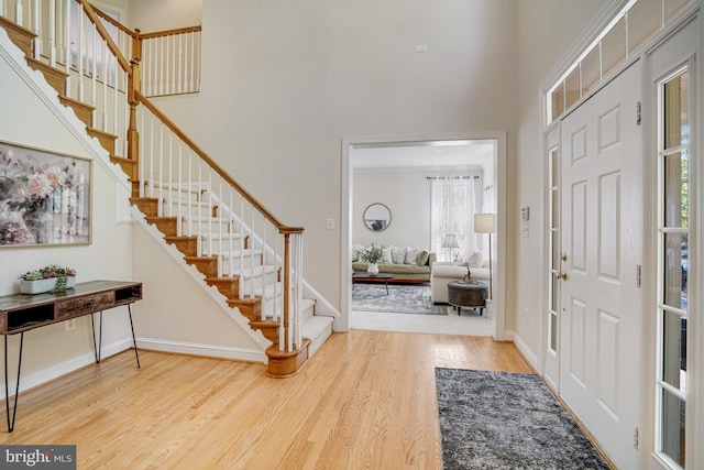 foyer with wood finished floors, stairs, a high ceiling, and a wealth of natural light