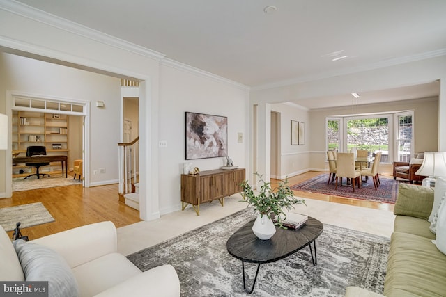 living room featuring baseboards, ornamental molding, wood finished floors, and stairway