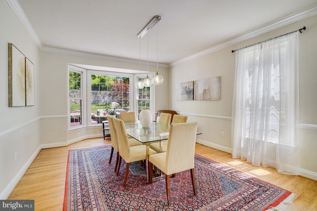 dining room featuring baseboards, ornamental molding, and light wood-style flooring