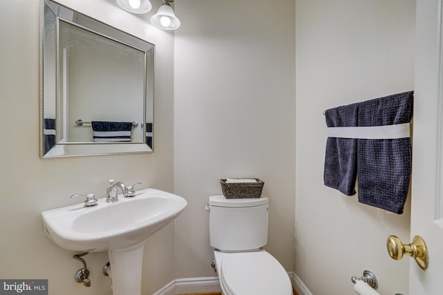 half bath with baseboards and toilet