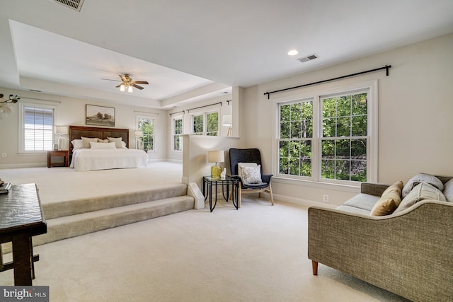 carpeted bedroom with baseboards, ceiling fan, a tray ceiling, and visible vents