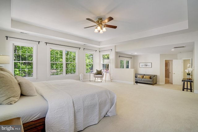 carpeted bedroom with a tray ceiling, visible vents, and baseboards