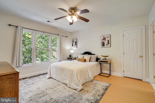 bedroom with a ceiling fan, baseboards, visible vents, and light wood-style flooring