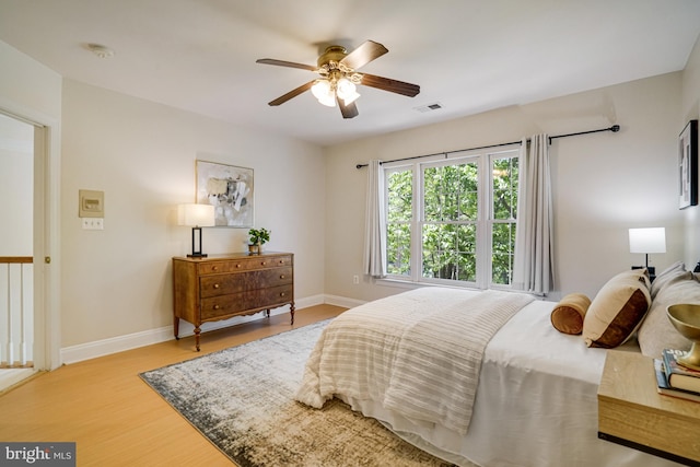 bedroom featuring visible vents, baseboards, ceiling fan, and wood finished floors