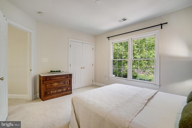 bedroom with light colored carpet, baseboards, visible vents, and a closet