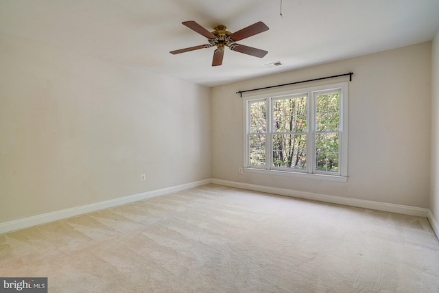 carpeted spare room featuring baseboards, ceiling fan, and visible vents