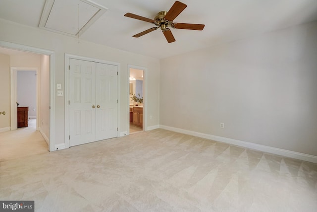 unfurnished bedroom featuring a closet, baseboards, attic access, and light colored carpet