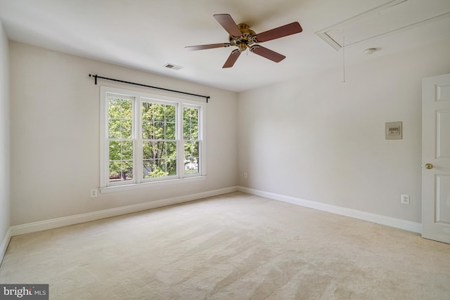 spare room with a ceiling fan, light colored carpet, visible vents, and attic access